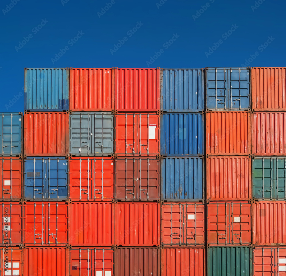 Grid of shipping containers stacked against a blue sky Grid of shipping containers stacked against a blue sky