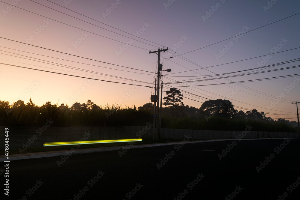Street lighting pole silhouettes of tree at sunrise in rural area of Guatemala, Central America.