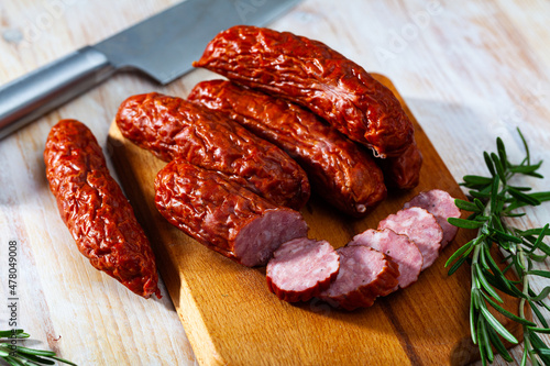 Popular czech smoked pork sausages with fresh rosemary on wooden table..
