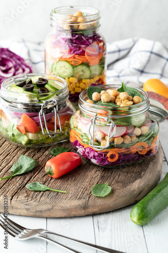 Close up of homemade salad jars served on a rustic wooden board.