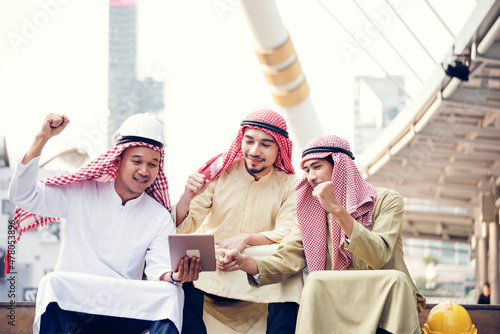Arab team hold digital tablet uae union teamwork people. Digital marketing arab group of people using smart tablet discuss modern muslim UAE city. Entrepreneur Asian people smile teams meeting.