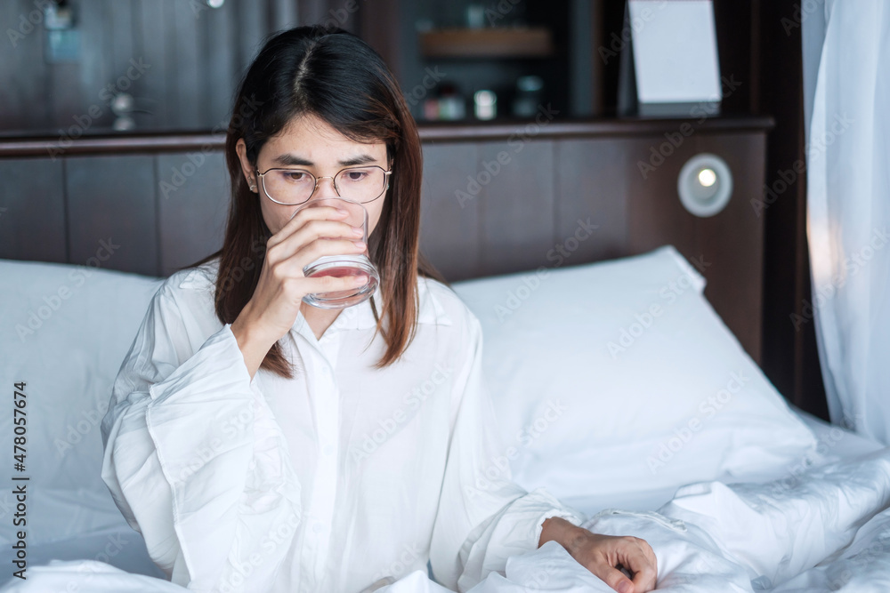 Happy woman holding water glass, female drinking pure water on bed at home. Healthy, Refreshment, lifestyle concept Happy woman holding water glass, female drinking pure water on bed at home. Healthy, Refreshment, lifestyle concept