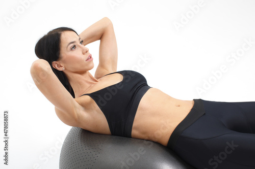 young athletic woman doing abs crunch exercise on fitness ball isolated on white background