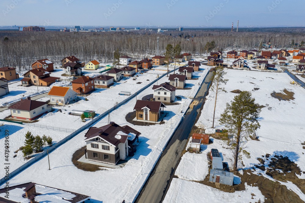 Aerial view of a cottage settlement under construction in the forest in Siberia in spring