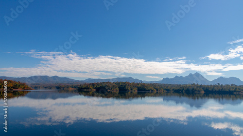 Kiew Kho Ma Dam with big  mountain as backdrop, Wide lake with blue sky and white fluffy clouds background, Located on Ban Huai Sanao Village, Pong Don, Chae Hom District, Lampang Province, Thailand. © Sarawut