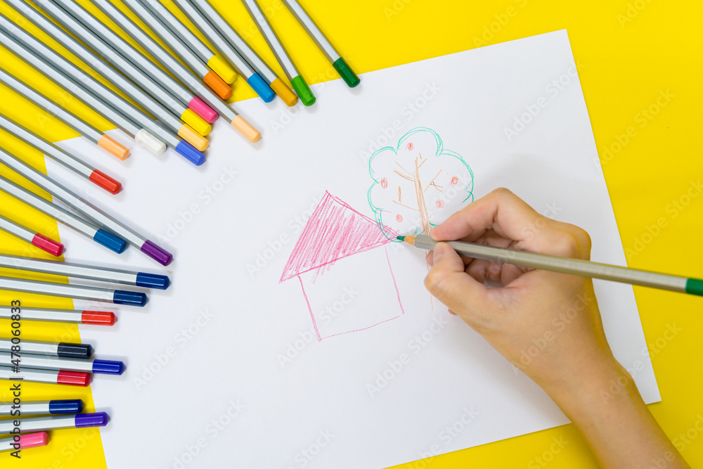 Close up of kid hands drawing with Colorful stationary school supplies on white trending background with copyspace or text flat lay. Colorful Education or back to school Concept Close up of kid hands drawing with Colorful stationary school supplies on white trending background with copyspace or text flat lay. Colorful Education or back to school Concept