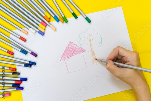 Close up of kid hands drawing with Colorful stationary school supplies on white trending background with copyspace or text flat lay. Colorful Education or back to school Concept
