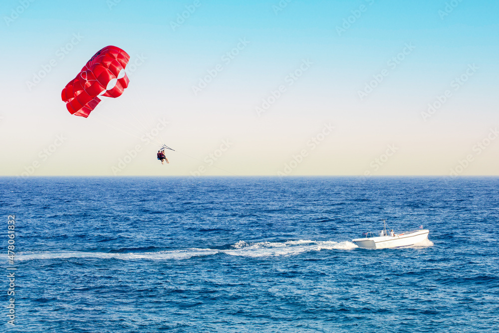 Red parasail wing pulled by a boat. Positive human emotions, feelings, family, travel, vacation. Red parasail wing pulled by a boat. Positive human emotions, feelings, family, travel, vacation.