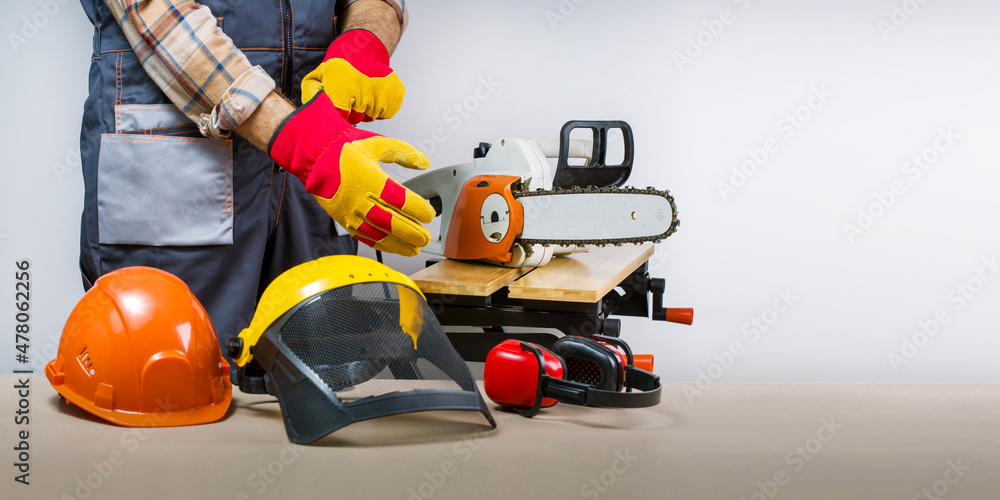 Worker puts on gloves, protective equipment for occupational safety  work.  lumberjack with protective equipment. Banner. - obrazy, fototapety, plakaty 
