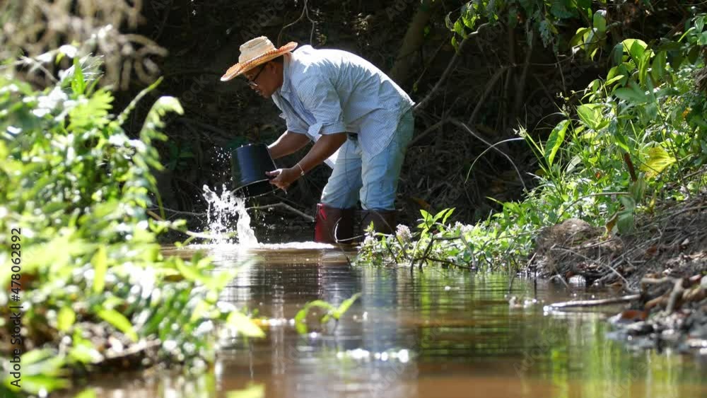 Asian man washing plant pots inside a small water canal. Working concept of agriculture with nature. Asian man washing plant pots inside a small water canal. Working concept of agriculture with nature.