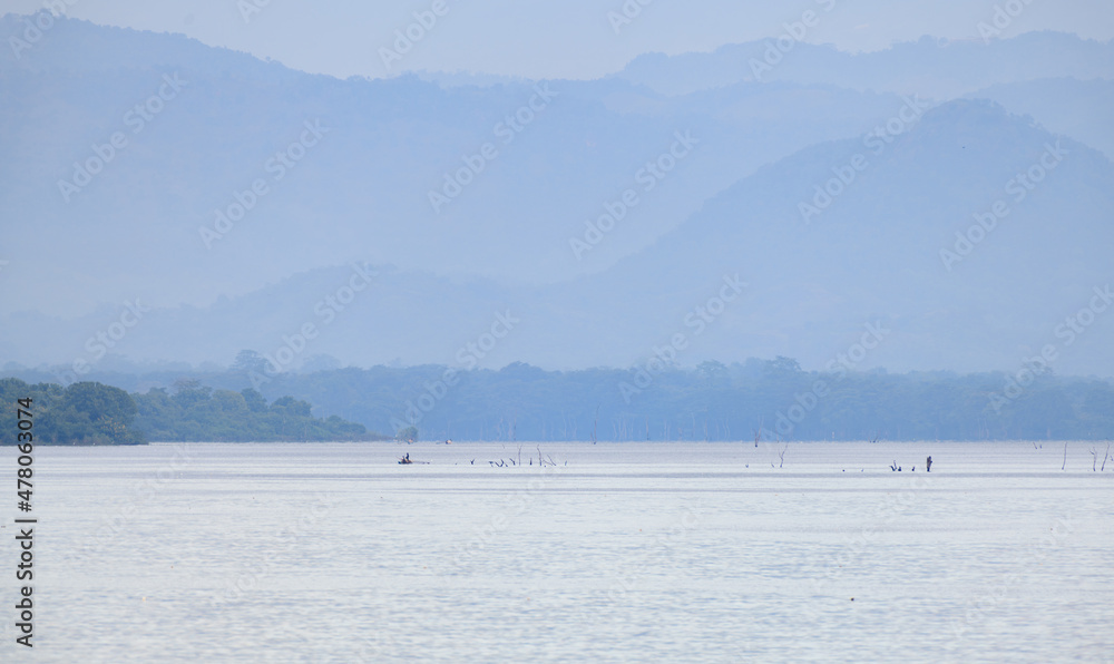 Cascade misty mountain range and the hazy morning in the Udawalawe national reservoir scenic landscape view.