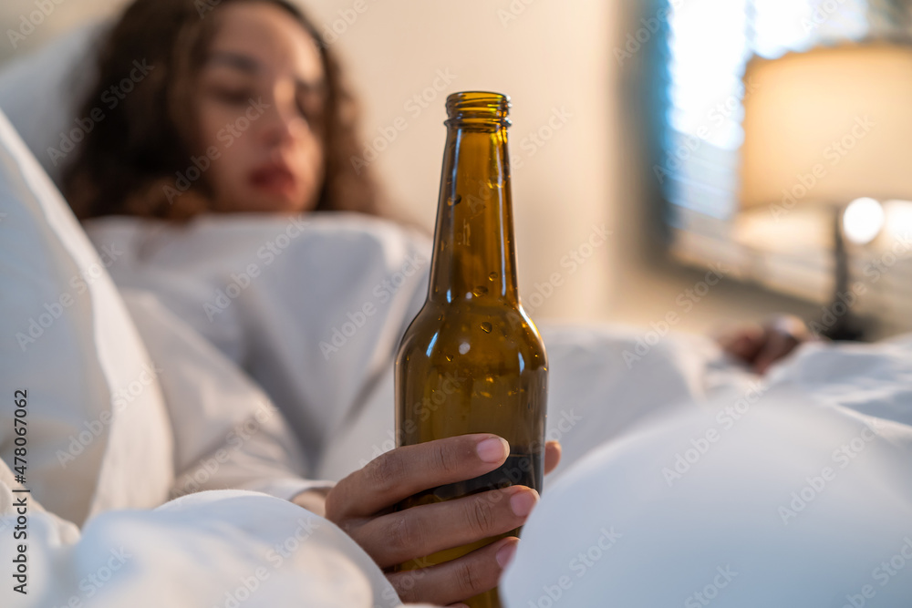 Drunk Latino woman hold beer bottle, and crying feel hangover on bed. Drunk Latino woman hold beer bottle, and crying feel hangover on bed.