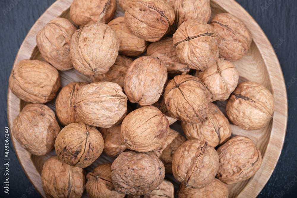 Group of walnuts on a black background. Nuts on a wooden plate. Walnut on black top view. Group of walnuts on a black background. Nuts on a wooden plate. Walnut on black top view.