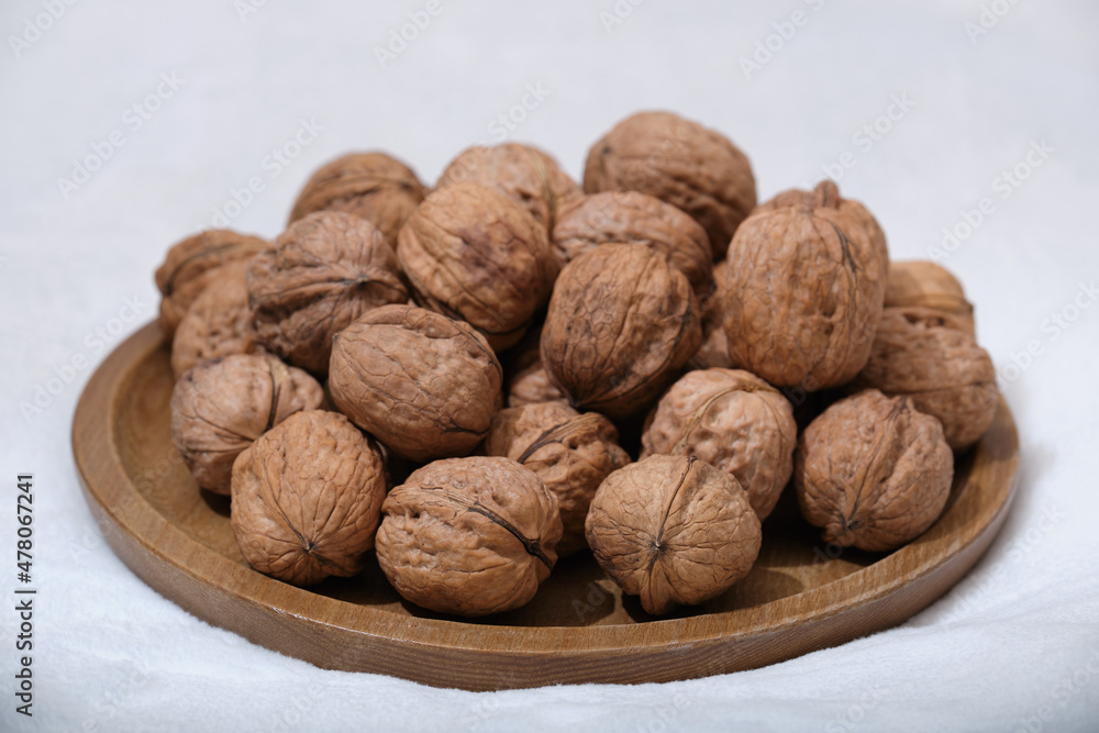 Group of walnuts on a white background. Nuts on a wooden plate. Walnut top view. Group of walnuts on a white background. Nuts on a wooden plate. Walnut top view.
