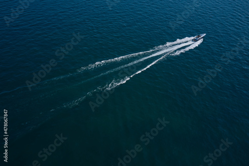Boat performance fast movement on the water aerial view. High-speed luxury boat diagonal movement on dark blue water. © Berg