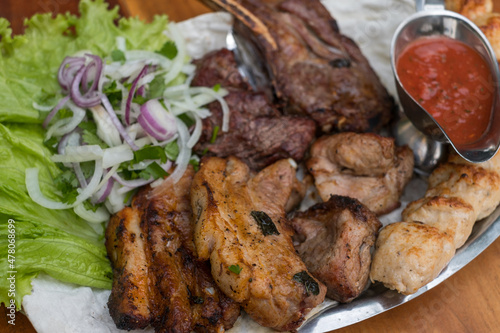 Assorted delicious grilled meat with lettuce and onion. Mixed grilled bbq meat with tomato sauce.Lamb, chicken. Top view, close up with copy space.