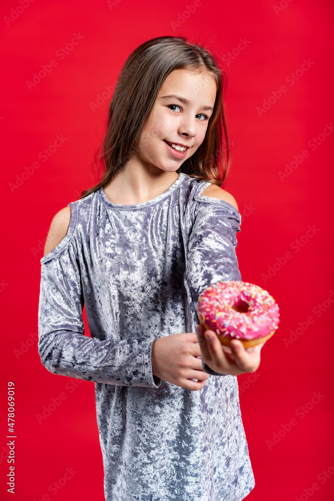 portrait of a beautiful girl in a gray dress with loose hair. teenager with donut. on a red background portrait of a beautiful girl in a gray dress with loose hair. teenager with donut. on a red background