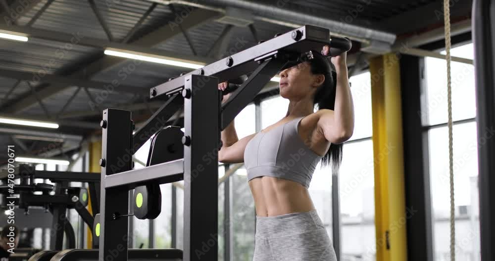 Portrait a young brunette woman dressed in workout clothes does exersises on the sport equipment for shoulders, biceps and back in a gym. The concept of the sports industry and active lifestyle. Portrait a young brunette woman dressed in workout clothes does exersises on the sport equipment for shoulders, biceps and back in a gym. The concept of the sports industry and active lifestyle.