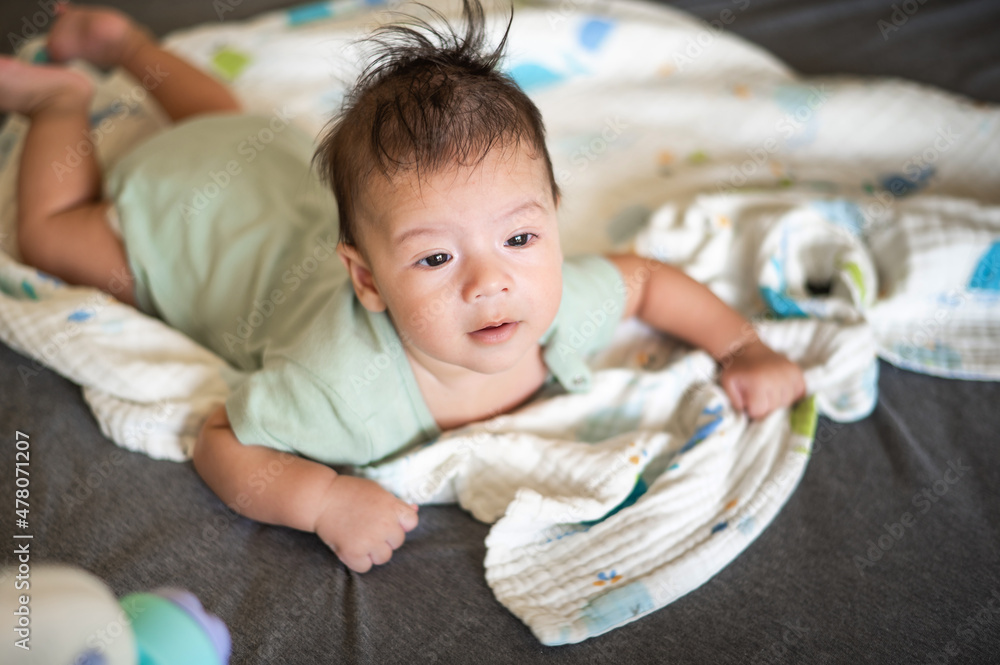 Adorable newborn baby boy lying on his tummy on the bed Adorable newborn baby boy lying on his tummy on the bed