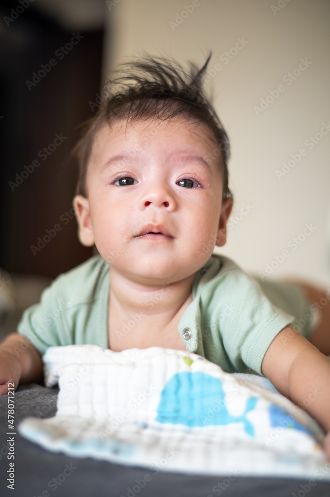 Adorable newborn baby boy lying on his tummy on the bed Adorable newborn baby boy lying on his tummy on the bed