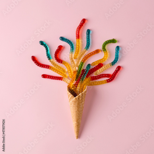 Ice cream cone with gummy candies on pink background.