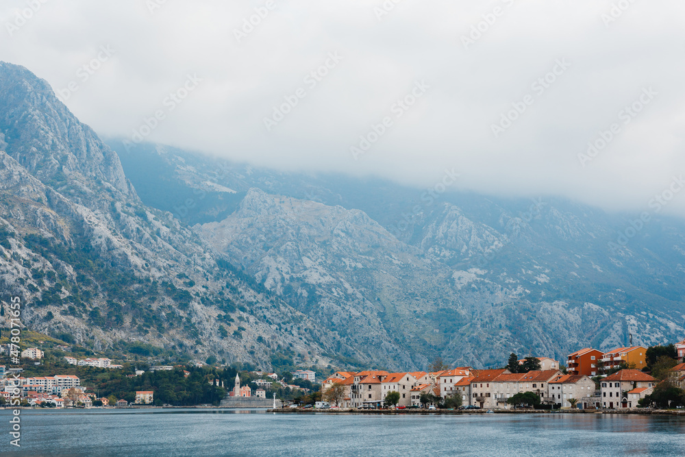 Old stone houses with red tiled roofs on the shore of the Bay of Kotor