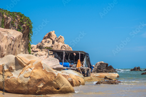 Real nature beauty view background. Sea ocean huge rocks stones coast bay landscape sun day blue sky, pale brown orange yellow boulders. Sailor hut with simple life style fishing gear. Vacation travel