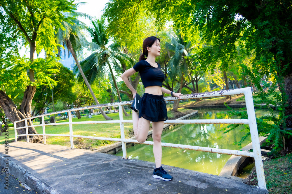 Asian woman waring a black dress warm up before jogging in the park