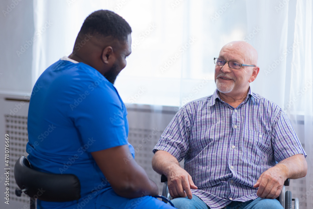 Obraz premium Caregiver and old man in a wheelchair. Professional nurse and patient in a nursing home. Assistance, rehabilitation and health care.