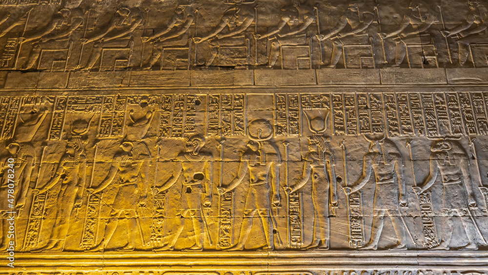 A fragment of the wall of an ancient Egyptian temple in Kom Ombo. Relief carvings of gods and hieroglyphs are visible. Close-up. Night illumination