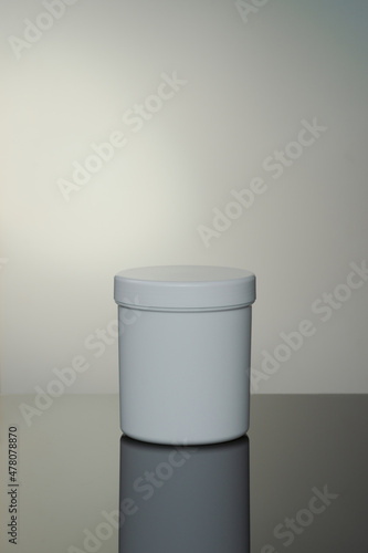 Mockup of white cosmetic jar with reflection on gray background