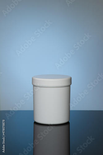 Mockup of white cosmetic jar with reflection on spot light blue background