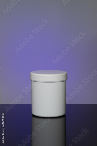 Mockup of white cosmetic jar with reflection on spot purple violet background