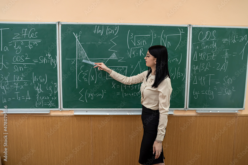 Beautiful female teacher near blackboard learn mathematical in classroom Beautiful female teacher near blackboard learn mathematical in classroom