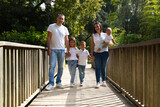 Portrait of happy parents with their three children walking on the wooden bridge. The eldest daughter is a transsexual girl. Concept of family happy united family with children.