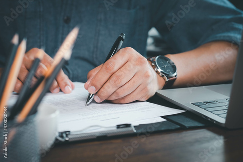 Close-up of Hand using writing pen with questionnaire or paperwork survey question filling in business company personal information form checklist document. photo