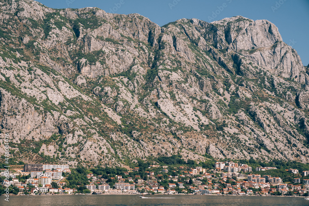Old stone houses at the foot of the mountain range on the shore of the Bay of Kotor
