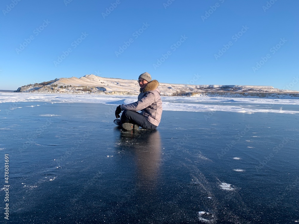 a man in winter meditates on the ice of the Volga river against the background of the hills a man in winter meditates on the ice of the Volga river against the background of the hills