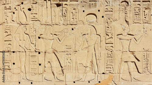 Carved bas-relief of god Amun and goddess Hathor with pharaoh. Close-up fragment, Karnak Temple, Luxor, Egypt. History, tourism or art history concept