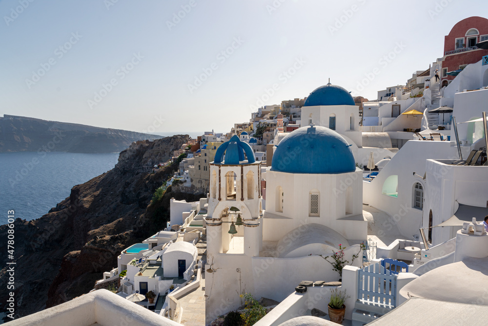 Oia, Greece - July 30, 2021: St. Anastasi and St. Spirydon and the Aegean sea in the background