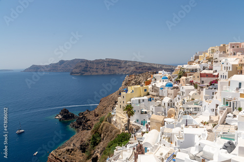 Oia, Greece - July 28, 2021: View of the town and the boat at the coastline