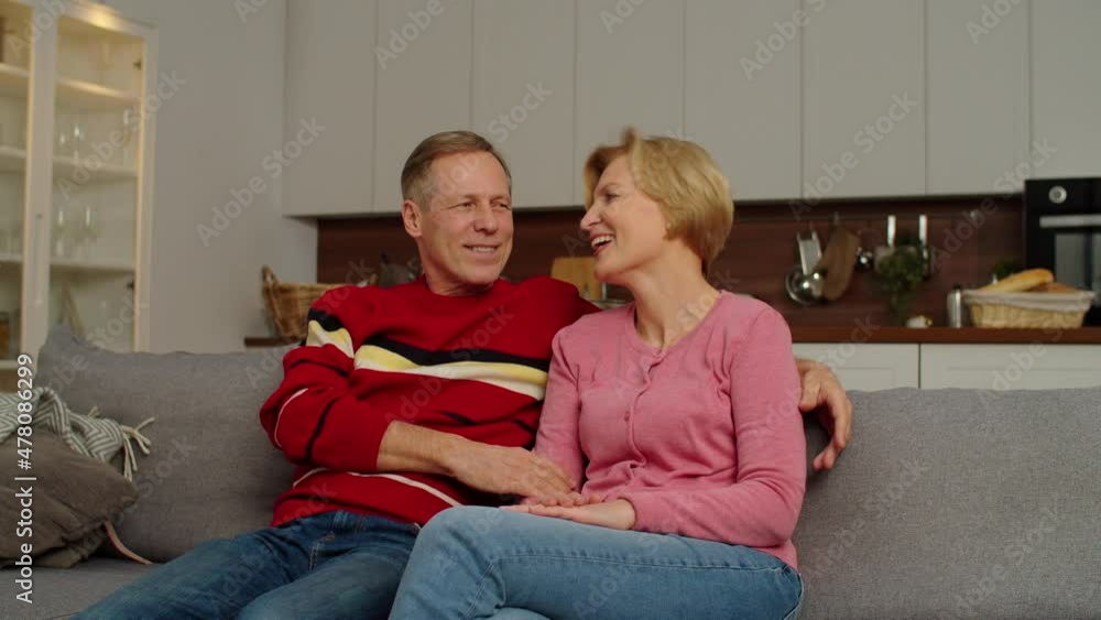 Playful affectionate school age multicultural kids embracing joyful middle aged grandparents, seated on sofa, from behind, expressing love, happiness and carefree mood while relaxing at home. Playful affectionate school age multicultural kids embracing joyful middle aged grandparents, seated on sofa, from behind, expressing love, happiness and carefree mood while relaxing at home.
