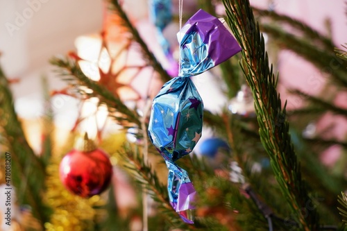 traditional Hungarian Christmas candy named szaloncukor in bright blue purple  packaging on the christmas tree