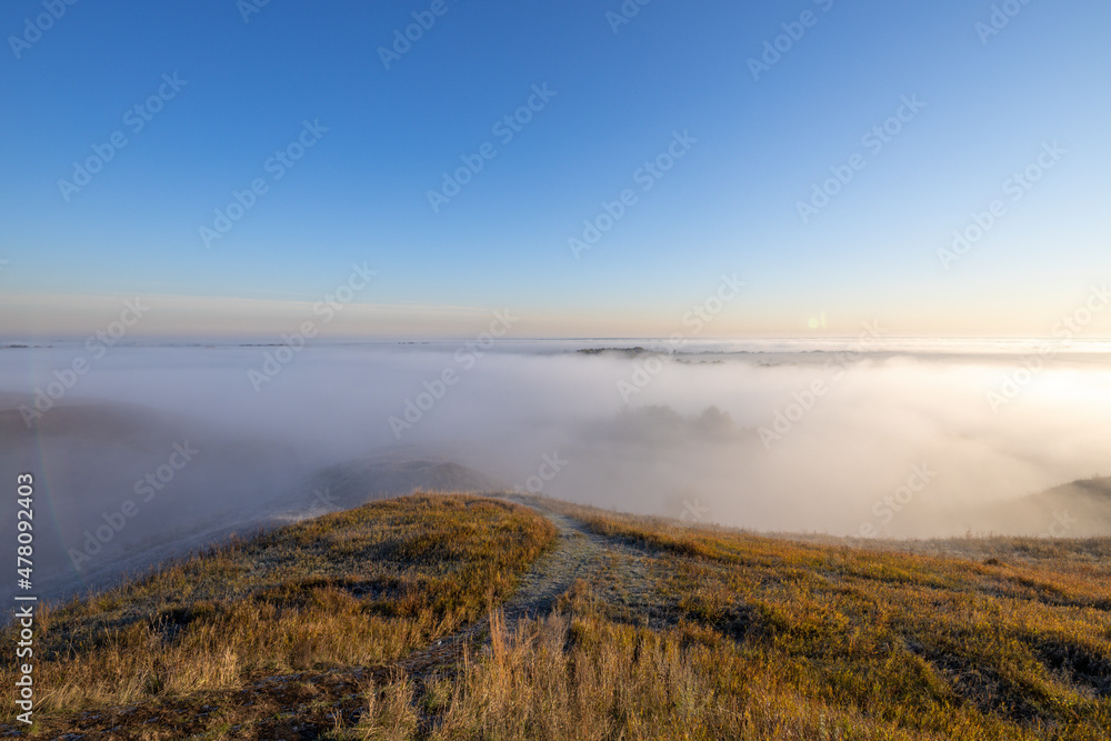 Autumn landscape in the early morning. Fog-covered expanses through which the first rays of the rising sun pass. Trees and hills in the fog. Dawn on a cold autumn morning. Autumn landscape in the early morning. Fog-covered expanses through which the first rays of the rising sun pass. Trees and hills in the fog. Dawn on a cold autumn morning.