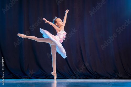 Fotografia little girl ballerina is dancing on stage in white tutu on pointe shoes classic variation