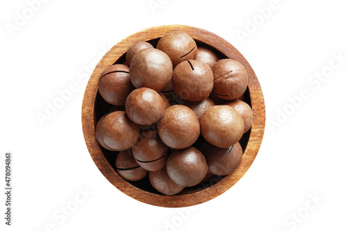 shelled macadamia nuts in wooden bowl isolated on white background. Vegan food, top view.