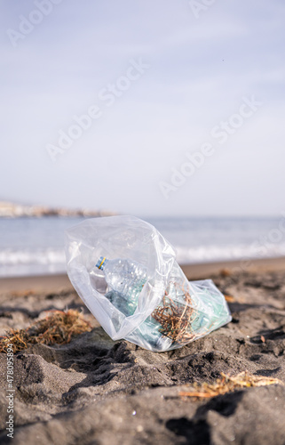 Garbage bag with plastic bottles on a beach, plastic collection on the coast, recycling, seabed cleanup and beach cleanup