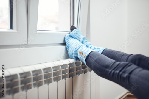 Woman's feet with woolen socks, enjoying inside home on the radiator.