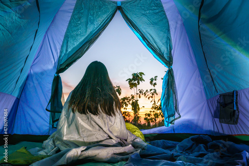 young girl relax inside the tent in the morning at sunrise in the forest. soft focus.