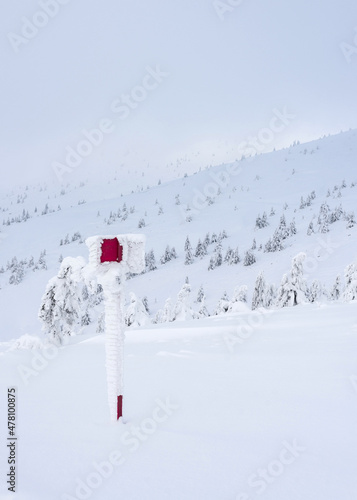 Snow covered red sign on the mountainside. Winter mountain landscape.